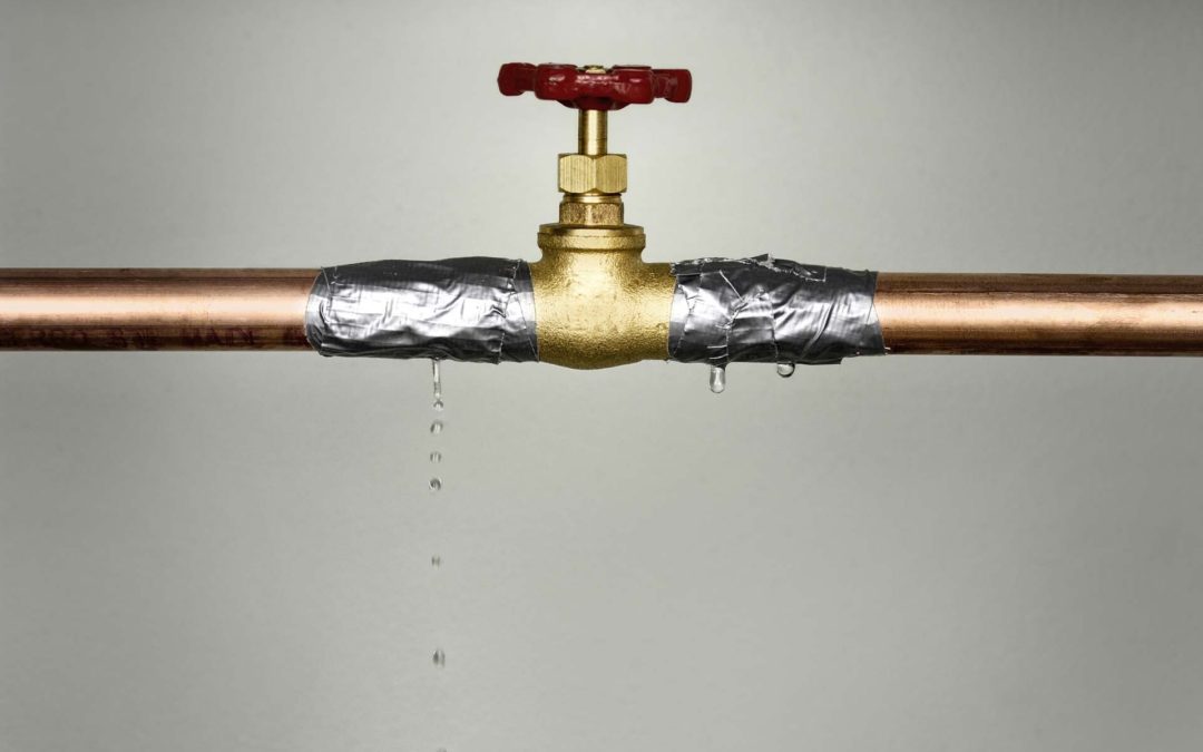 A closeup shot of the leaking water pipe with red valve.